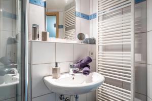 Un baño blanco con lavabo y espejo. en Haus Bienen, en Ihringen 23 fotos más