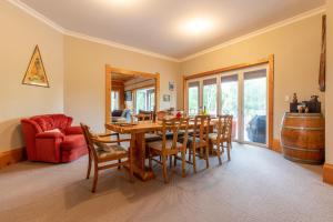a dining room with a table and chairs and a red couch at Hatuma Paradise in  Waipukurau