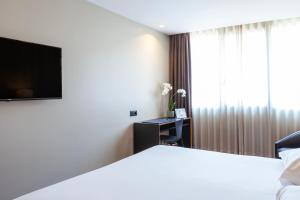 a hotel room with a bed and a flat screen tv at Hotel Fundador in Guimarães