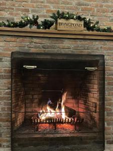 a brick fireplace with a fire in it at Longpond Farm House and Loft in Salisbury