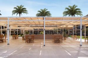 a patio with tables and chairs and palm trees at JAZ Lamaya Resort in Coraya Bay