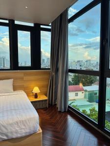 a bedroom with a bed and large windows at MAIA Hotel & Apartment Danang in Da Nang