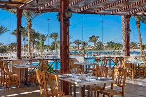 a restaurant with tables and chairs and a pool at JAZ Lamaya Resort in Coraya Bay