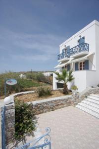 a white house with stairs and a balcony at Manos Apartments in Megas Yialos-Nites