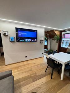 a living room with a table and a tv on a wall at Residenze Vezza - Il Larice - in Vezza dʼOglio