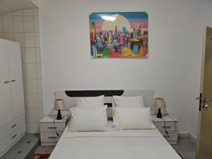 a bedroom with a white bed and a painting on the wall at Résidence Keur Antou in Ziguinchor