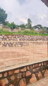a wooden fence in front of a stone wall at Garden House in Huye