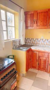 a kitchen with wooden cabinets and a sink and a stove at Garden House in Huye