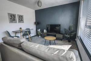 a living room with a couch and a tv at Comfy 1BR Apt, Self Check In, Free Parking by The Davis Collective in Derby
