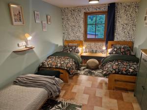 Un dormitorio con tres camas y una ventana. en Apartmány KOUTY 23, en Kouty