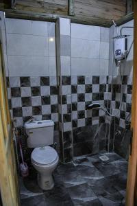 a bathroom with a toilet and a tiled wall at Rustic cabin in Masaka