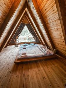 a bed in a wooden attic with a window at Merce Bungalov in Sakarya