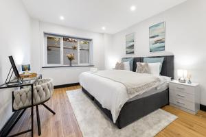 フィンチリーにあるModern Luxury 1 Bedroom Apartment with patio sleeps 4 10 min to tubeのベッドと机と2つの窓がある寝室