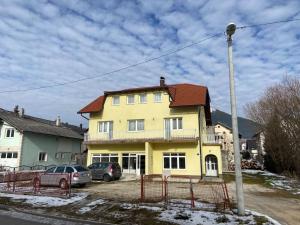 a yellow house with cars parked in front of it at Pansion Tomas Kupres in Kupres +23 photos