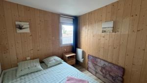 een slaapkamer met houten wanden en een bed met een raam bij Joli duplex 5 pers avec piscine - Cap Ferret in Lège-Cap-Ferret +20 foto's