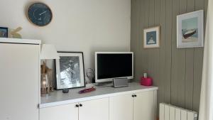 een televisie bovenop een kast met een klok bij Joli duplex 5 pers avec piscine - Cap Ferret in Lège-Cap-Ferret