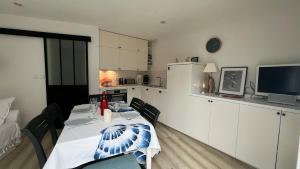 een eetkamer met een tafel en een keuken bij Joli duplex 5 pers avec piscine - Cap Ferret in Lège-Cap-Ferret