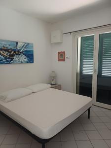 un grand lit blanc dans une chambre avec une fenêtre dans l'établissement casa del merlo, à Marina di Campo Airport