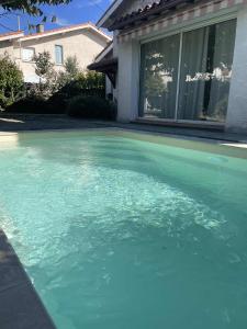 a pool of blue water in front of a house at Comme à la maison B and B in Carcassonne