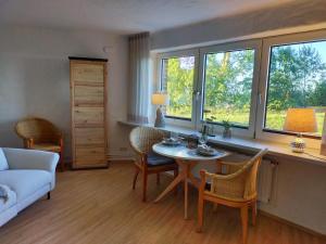 a living room with a table and chairs and windows at Lille Koje - Dein eigenes Strand-Apartment mit Panoramablick über die Ostsee in Kronsgaard
