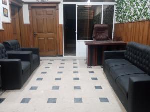 a waiting room with black couches and a chair at BHURBAN top APARTMENTs in Murree