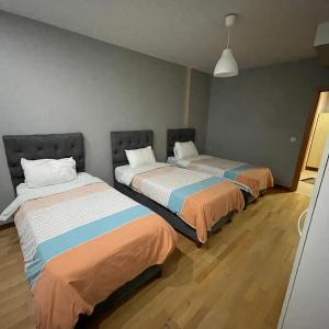 two beds in a room with wooden floors at Modern Comfort Steps from Taksim in Istanbul