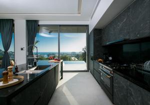 a kitchen with black cabinets and a large window at Villa Nordic Star Seaview Near Kata Beach in Kata Beach