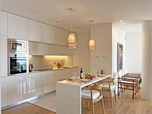 a kitchen with white cabinets and a table with chairs at Lady Delmar Marina Olhao By Junto ao Mar in Olhão