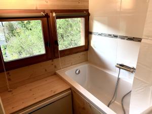 ein kleines Badezimmer mit Badewanne und zwei Fenstern in der Unterkunft Chalet individuel en montagne in La Forclaz + 8 Fotos