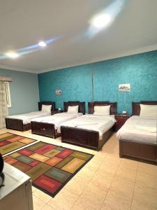 een kamer met drie bedden en een blauwe muur bij Elgabry pyramids inn in Caïro
