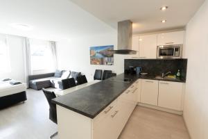 a kitchen with white cabinets and a black counter top at 306 London 59m2 4-8 Pers extra Bedroom in Klagenfurt