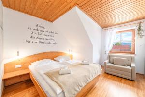 een slaapkamer met een groot bed en een stoel bij BioHAUS in Haus im Ennstal