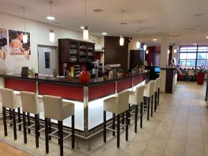a bar in a restaurant with white chairs at Matchpoint Hotel in Altdorf bei Nuernberg