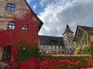 an old building with a clock tower and red ivy at Matchpoint Hotel in Altdorf bei Nuernberg