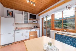 een keuken met witte kasten en een tafel met stoelen bij BioHAUS in Haus im Ennstal