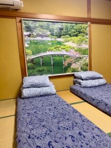 Dos camas en una habitación con una gran ventana. en 楓の宿1號館, en Osaka