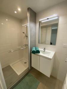 a white bathroom with a sink and a shower at Le Palmier in Valras-Plage