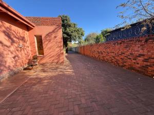 un trottoir en briques à côté d'un mur en briques dans l'établissement Bushveld Inn Guest House, à Potgietersrus
