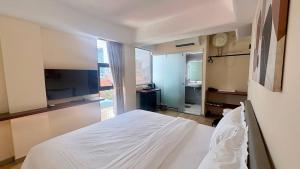 Un dormitorio con una cama blanca y un televisor. en The Guesthouse By SH, en Phnom Penh