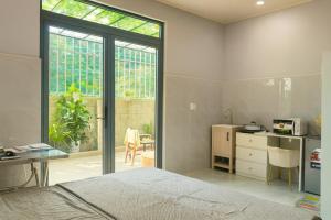 a bedroom with a bed and a table and a kitchen at Happy House Sài Gòn in Ho Chi Minh City