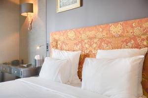 a bed with white pillows and an orange headboard at New Hotel République in Paris