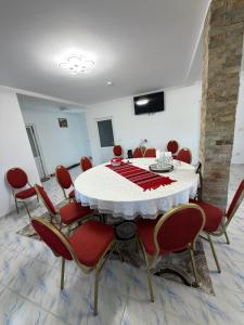 comedor con mesa blanca y sillas rojas en Căsuța din livadă, en Capu Cîmpului