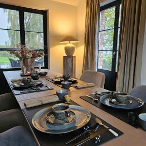 a dining room table with dishes on it with windows at LA BELLE IDEE in Nokere