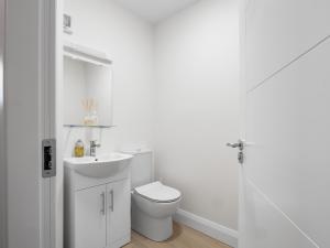 a white bathroom with a toilet and a sink at 17 Clifden Court in Clifden +16 photos