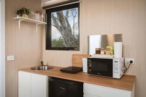 a kitchen counter with a microwave and a sink at Hollow Mountain Getaway 2 by Tiny Away in Laharum +16 photos