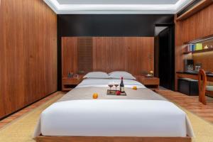 a bedroom with a large white bed with a bottle of wine at Floral Hotel in Datong