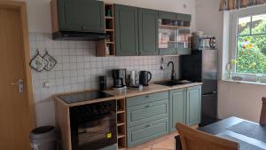 a kitchen with green cabinets and a black refrigerator at " FeWo am Hof " Große Wohnung mit zwei Schlafzimmern, seperate Küche und großem Bad in Beverstedt