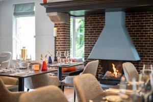 ein Restaurant mit Tischen, Stühlen und einem Kamin in der Unterkunft Bilderberg Grand Hotel Wientjes in Zwolle