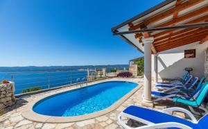 a swimming pool with chairs next to a house at Villa Marevista in Lokva Rogoznica
