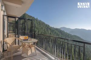 a balcony with a table and chairs and mountains at StayVista at Ved Vilas in Kīar